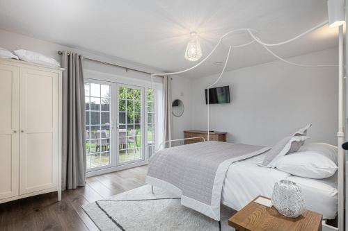 a white bedroom with a bed and a window at Felin Traeth Cottage in Rhosneigr