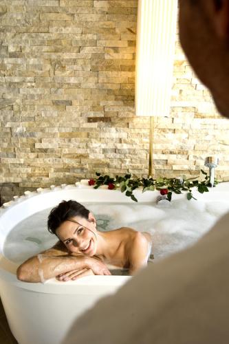 a woman laying in a bath tub in a bathroom at Hotel Chalet Tianes - Alpine Relax in Castelrotto