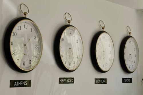 four clocks are hanging on a wall at Bond Smart Living Suites in Athens