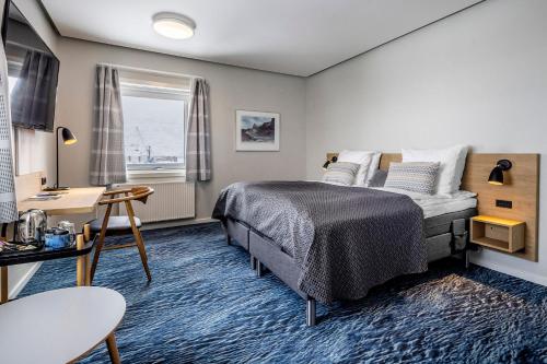 a bedroom with a bed and a desk and a window at HOTEL SØMA Nuuk in Nuuk