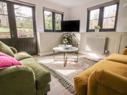 a living room with two couches and a table at Cherry Orchard Farm in Maidstone