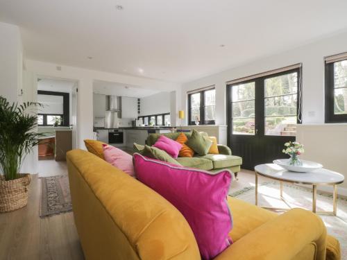 a living room with a yellow couch with colorful pillows at Cherry Orchard Farm in Maidstone