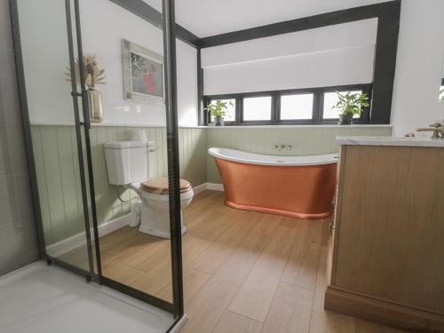 a bathroom with a bath tub and a toilet at Cherry Orchard Farm in Maidstone