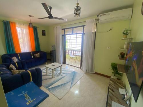 a living room with a blue couch and a table at Modern 1-Bedroom Apartment with AC & Parking along Mtwapa Beach Road in Mtwapa