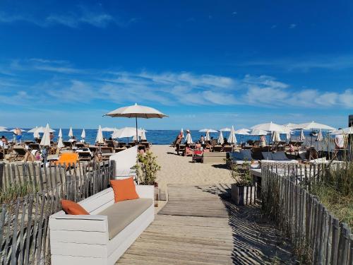 Un sofá blanco en una pasarela de madera hacia la playa. en Saint-Tropez FLORIDA, en Saint-Tropez