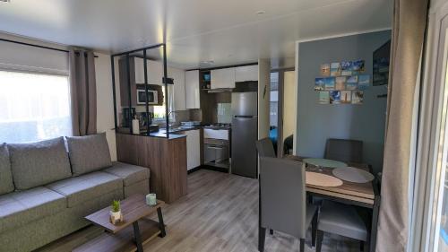un salon et une cuisine avec un canapé et une table dans l'établissement Mobil-home 40m2 au calme, plage, piscine, forêt, à Saint-Julien-en-Born