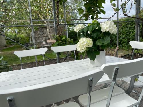 a white table and chairs with a vase of flowers at Nyhamnsläge med sundsutsikt och nära till strand. in Nyhamnsläge