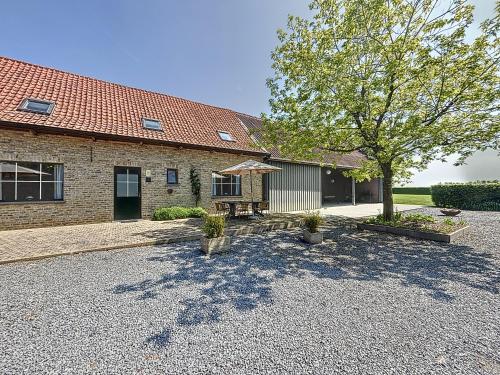 a building with a table and a tree in front of it at De Eikhoeve - Alveringem in Alveringem