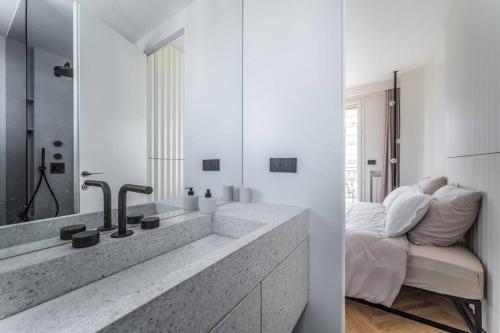 - deux vues sur une salle de bains avec lavabo et une chambre dans l'établissement Haussman Palace Appartment, à Paris