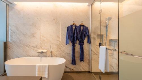 a bathroom with a shower and a tub and a sink at Chatrium Grand Bangkok in Bangkok