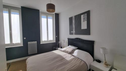 a bedroom with a bed and two windows at Maison de ville Royan centre - Meublé tourisme 4 étoiles in Royan