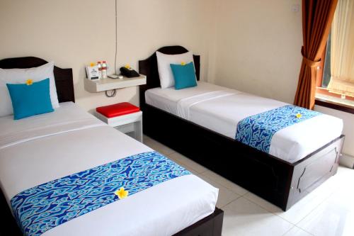 um quarto com duas camas com lençóis azuis e brancos em Djembank Hotel em Tjakranegara