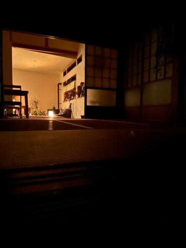 a dark room with a building with a door open at 白子の古民家bimbetta 星空の下で焚き火とバーベキュー in Shirako