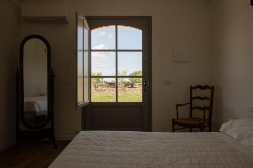a bedroom with a bed and a window and a mirror at Masseria Celentano Relais & Agriturismo in San Severo