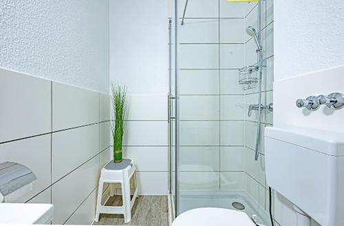 a bathroom with a shower and a toilet and a stool at fewo1846 - Strandresidenz Wassersleben Nele - Studioapartment mit Balkon und Meerblick in Harrislee