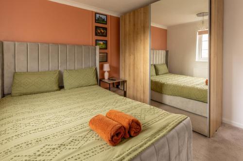 ein Schlafzimmer mit einem Bett mit einem orangenen Handtuch darauf in der Unterkunft Ideal 3 Bed Home In Glasgow City With Free Parking in Glasgow