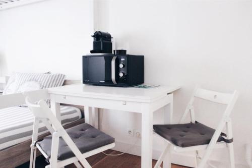 - un four micro-ondes assis sur une table blanche avec deux chaises dans l'établissement Sacre Coeur Flat, à Paris