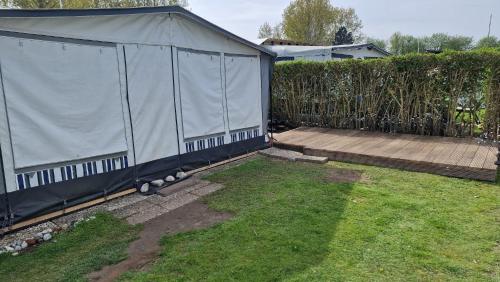 a tent in a yard next to a fence at Wohnwagen auf dem Wulfenerhals ca 150m bis zum Meer in Fehmarn