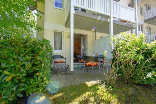 eine Terrasse mit Stühlen und einem Tisch vor einem Gebäude in der Unterkunft Wohnpark Stadt Hamburg - Apt. 14 in Binz