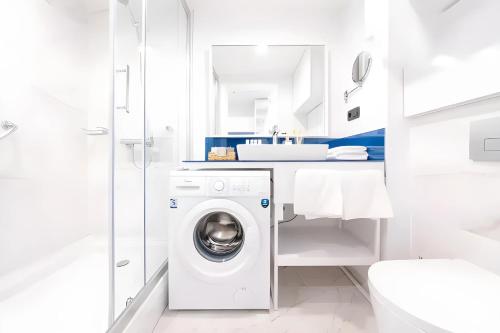 a white bathroom with a washing machine in it at Orbi City Lux in Batumi