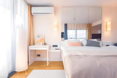 a white bedroom with a bed and a desk at Orbi City Lux in Batumi