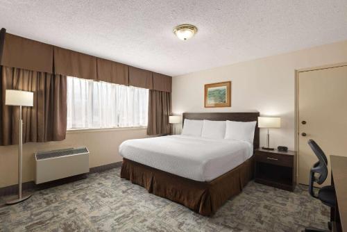 a hotel room with a bed and a window at Travelodge by Wyndham Thunder Bay ON in Thunder Bay
