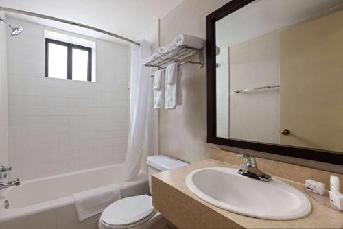 a bathroom with a sink and a toilet and a mirror at Travelodge by Wyndham Thunder Bay ON in Thunder Bay