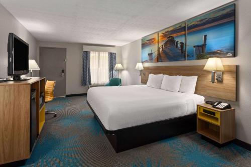 a hotel room with a bed and a flat screen tv at Days Inn by Wyndham Douglasville-Atlanta-Fairburn Road in Douglasville