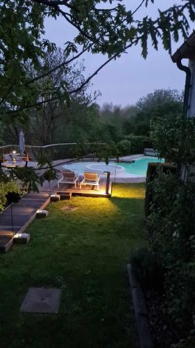 a backyard with a pool with benches and a swimming pool at Gîte 7 personnes- Le Refuge du Saule in Burdinne