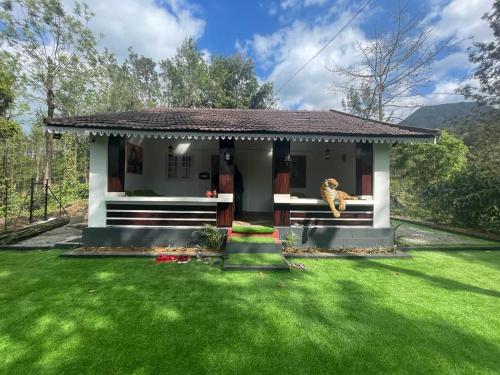 a small house with a green lawn in front of it at Yuk's villa in Gūdalūr