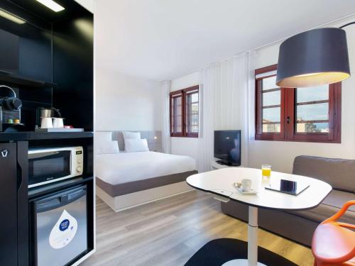 ペルピニャンにあるNovotel Suites Perpignan Centreのベッド付きの部屋とテーブル付きの部屋