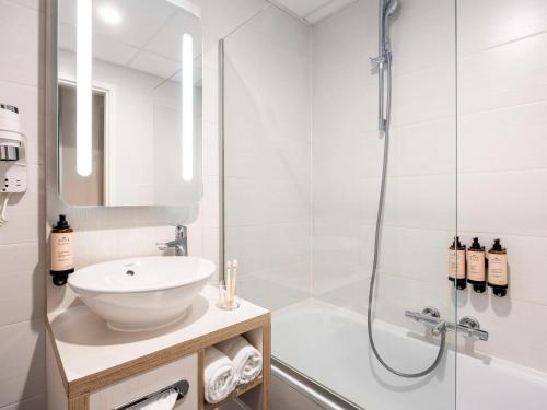 een witte badkamer met een wastafel en een douche bij Mercure Oostende in Oostende