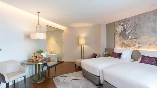 a hotel room with two beds and a table at Chatrium Grand Bangkok in Bangkok