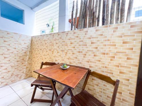 a wooden table and two chairs in front of a brick wall at Pousada Sol e Mar in Morro de São Paulo