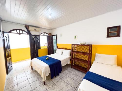 Duas camas num quarto com paredes amarelas e brancas em Pousada Sol e Mar em Morro de São Paulo