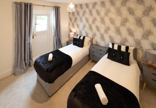 1 dormitorio con 2 camas y pared en Royal Retreat & Lego Lodge with free parking! en Windsor