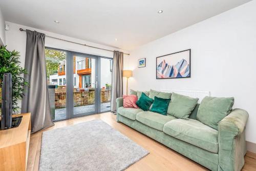 sala de estar con sofá verde y ventana grande en Pass the Keys Modern Home-Private Parking-Garden en Londres