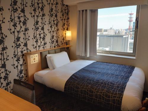 a hotel room with a bed and a window at APA Hotel Kagoshima Chuo-Ekimae in Kagoshima