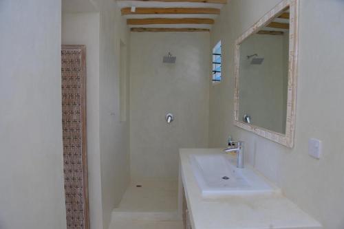 a white bathroom with a sink and a mirror at Ahadi villas in Mombasa