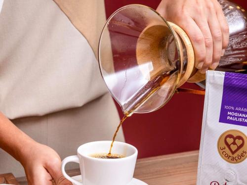 a person pouring coffee into a cup on a table at Grand Mercure Rio de Janeiro Copacabana in Rio de Janeiro