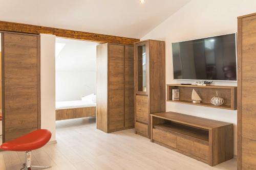 un soggiorno con TV e sedia rossa di Hotel Lavender - Oleander Resort a Strunjan