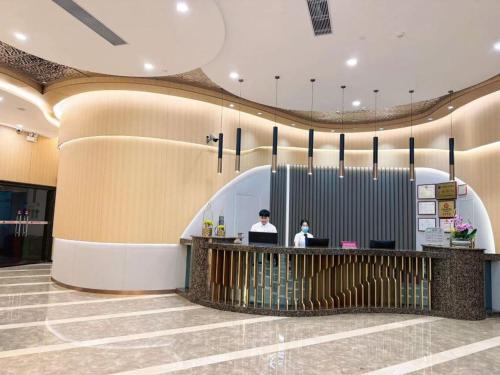 a lobby with two people sitting at a counter at Mizparton Hotel South Qianjin Road in Heshan