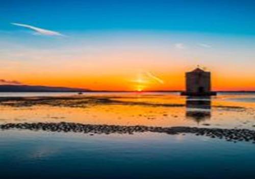 a lighthouse on the beach with the sunset in the background at App - Il Fenicottero con parcheggio gratuito ad Orbetello in Orbetello