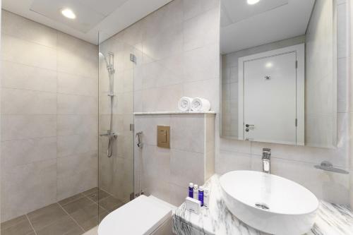La salle de bains blanche est pourvue d'un lavabo et d'une douche. dans l'établissement Maison Privee - City Chic Retreat in Dubai Prime Location, à Dubaï