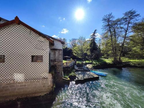 a river with a building and boats in it at Moulin de Courcelles in Aubréville