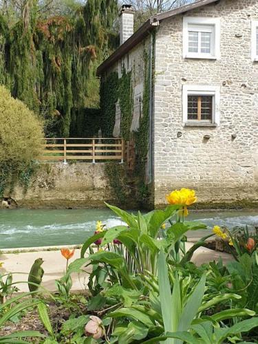 a building next to a river with a bridge at Moulin de Courcelles in Aubréville