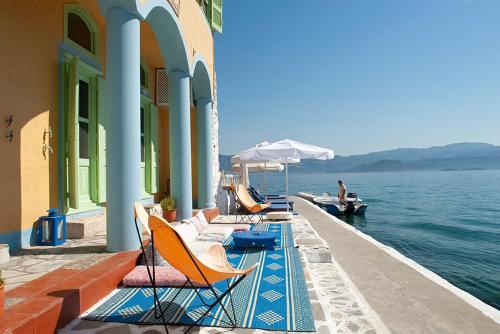 een rij stoelen en parasols op een steiger met water bij Mediterraneo Hotel in Meyisti