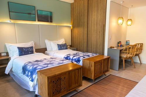 a bedroom with two beds and a desk and a table at Wyndham Ilhabela Casa Di Sirena in Ilhabela