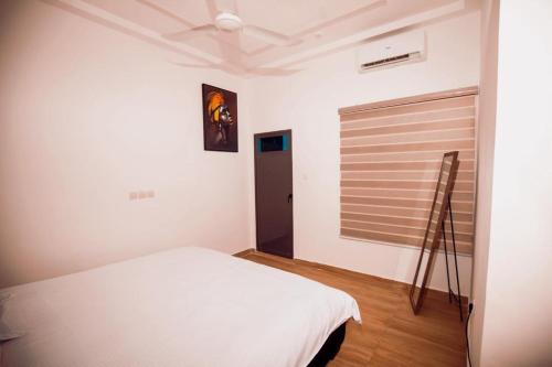 1 dormitorio con cama blanca y ventana en Appartement meublé type T2, en Godomè