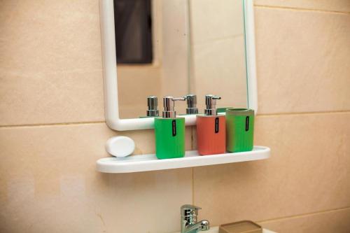 a bathroom sink with four cups on a shelf under a mirror at Appartement meublé type T2 in Godomè